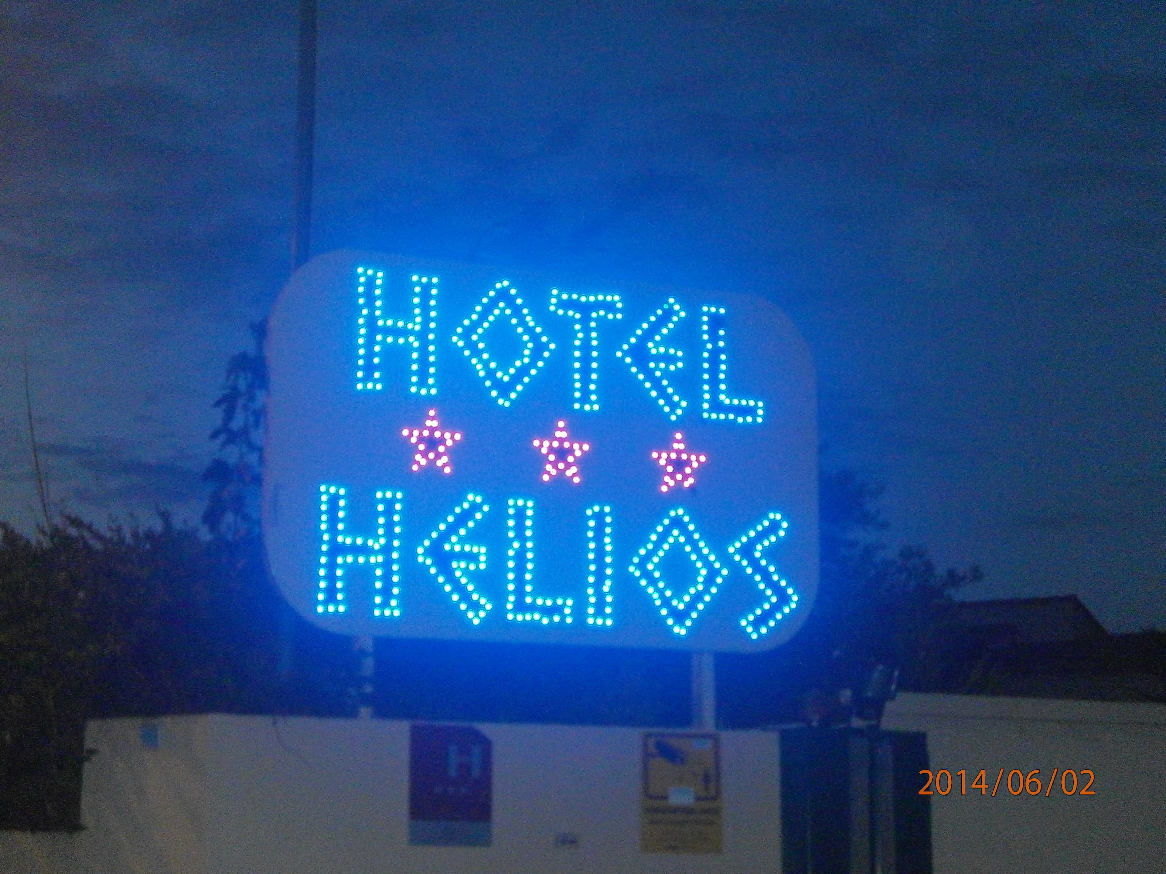 A neon sign for a hotel with the name "HOTEL HELIOS" and three stars.