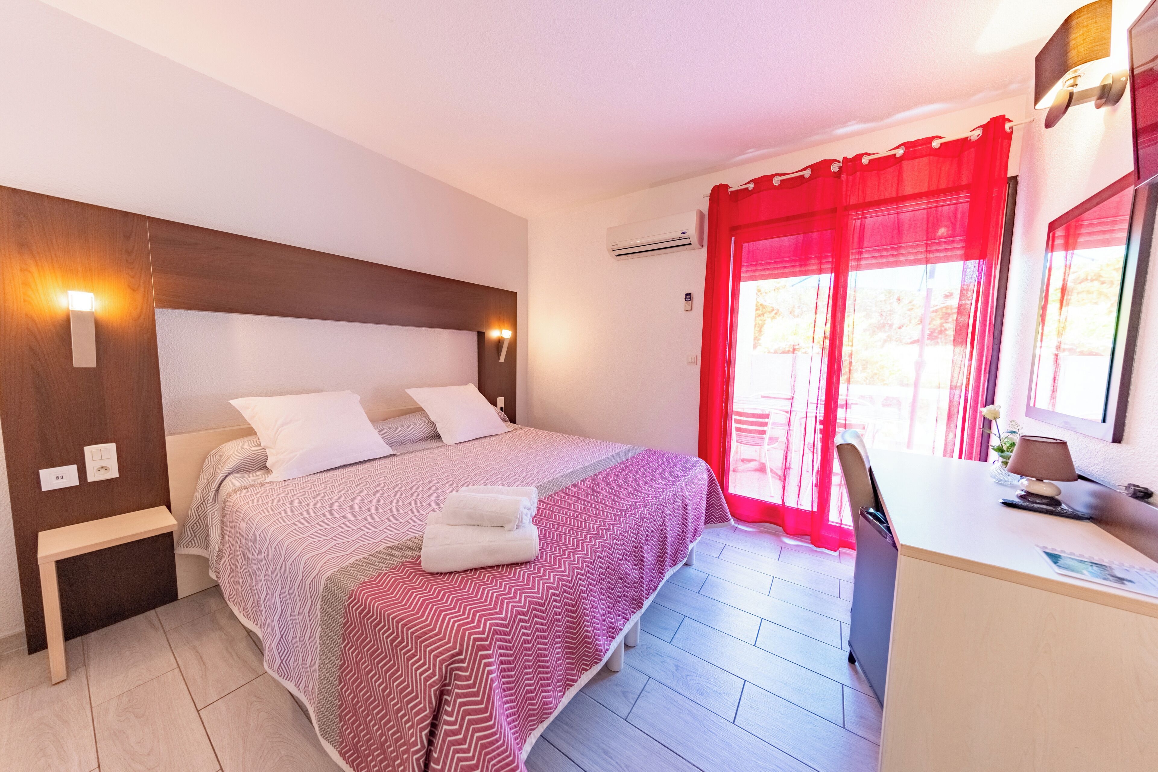 Un dormitorio con cama, mesita de noche, escritorio y silla.