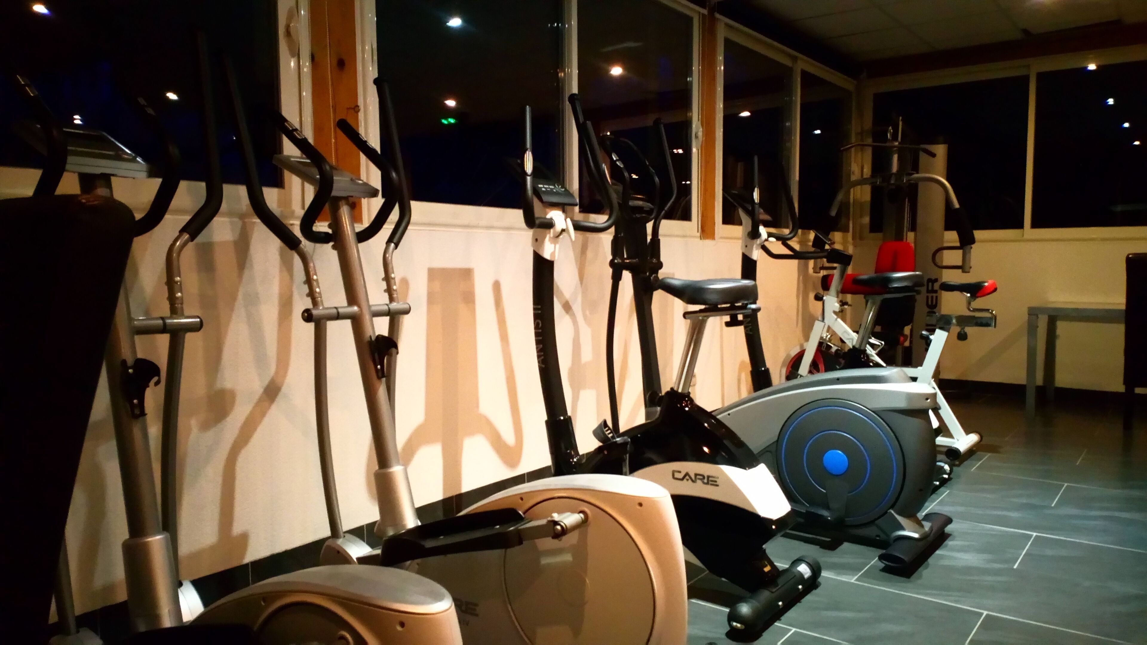 A gym with various exercise equipment including treadmills, stationary bikes, and elliptical machines.