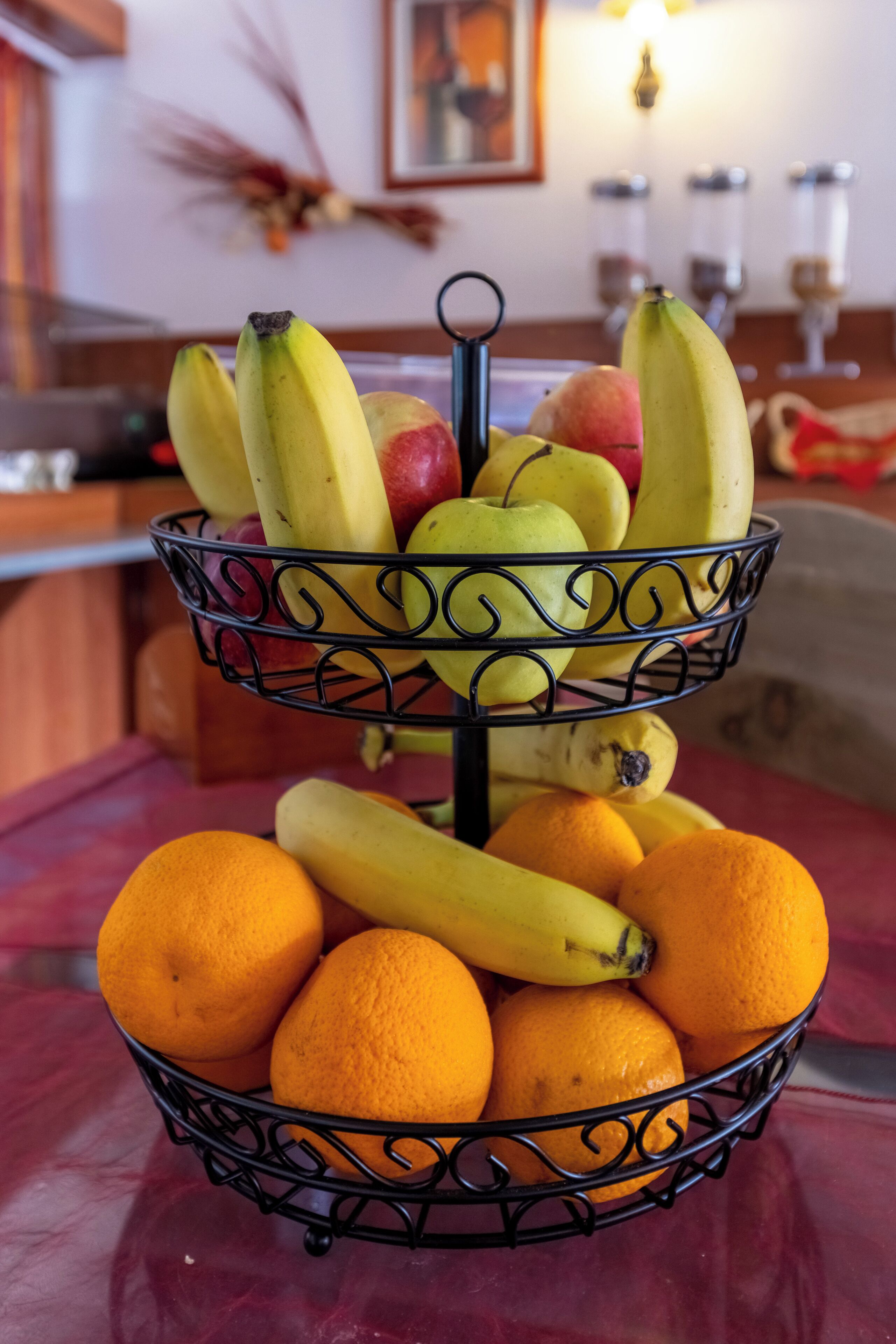 Un panier de fruits contenant des bananes, des pommes et des oranges, posé sur une table.
