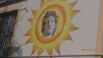 A building with a mural of a sun and a classical statue.
