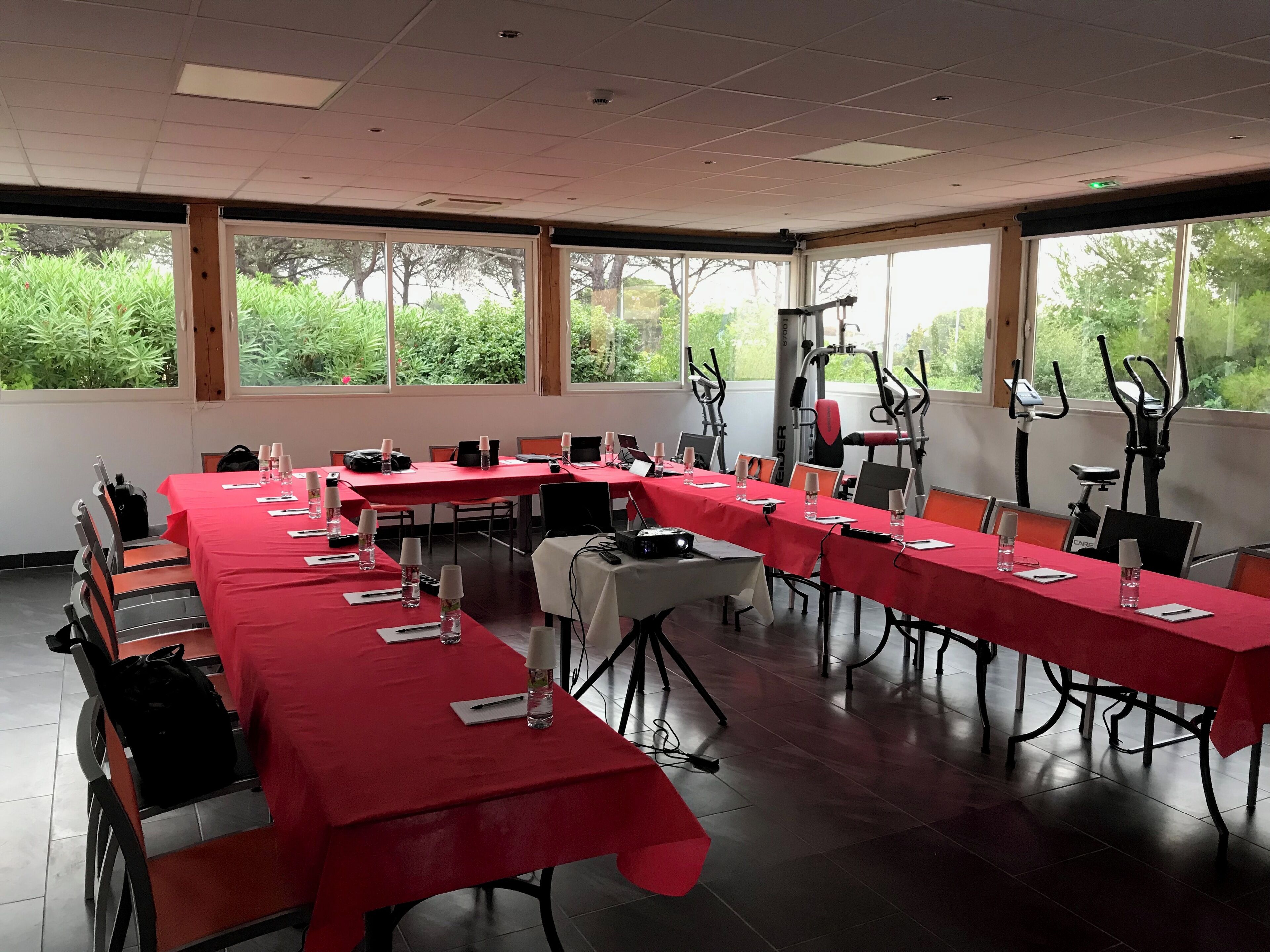 A conference room with red tables, chairs, and exercise equipment.