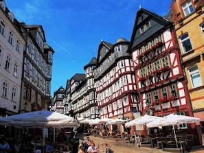 Une rue typique d’Europe, avec ses bâtiments à colombages, ses terrasses et un ciel d’un bleu éclatant.