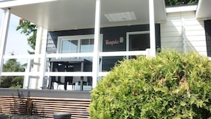 Un edificio moderno con un área exterior techada, un letrero que dice "Tropic" y un jardín bien cuidado.