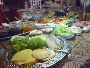 Un buffet proposant une variété d’aliments, notamment des fromages, des fruits et des légumes.