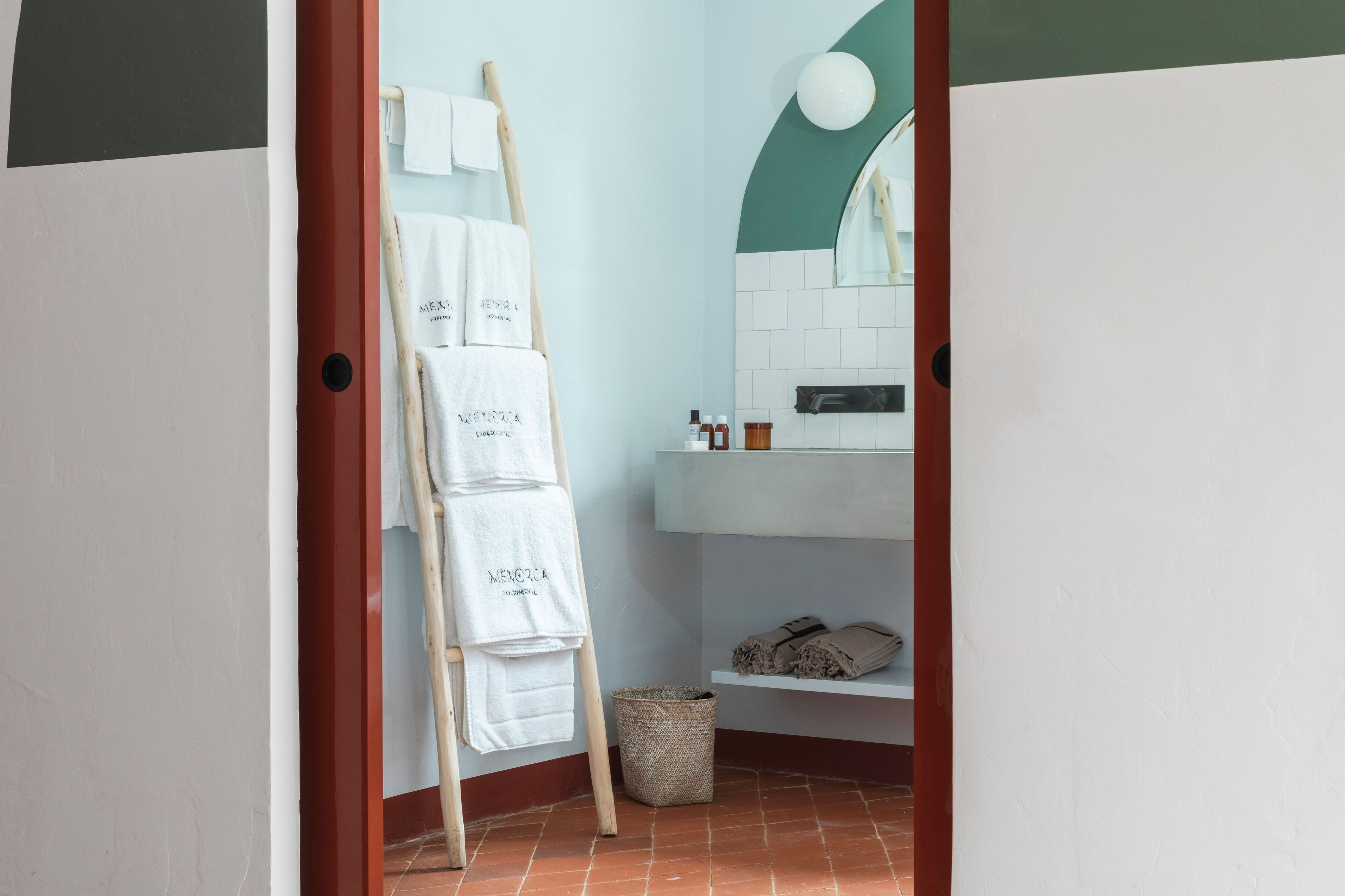 Une salle de bain avec un lavabo blanc, un miroir et un porte-serviettes avec des serviettes.