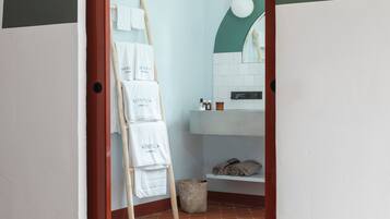 Une salle de bain avec un lavabo blanc, un miroir et un porte-serviettes avec des serviettes.