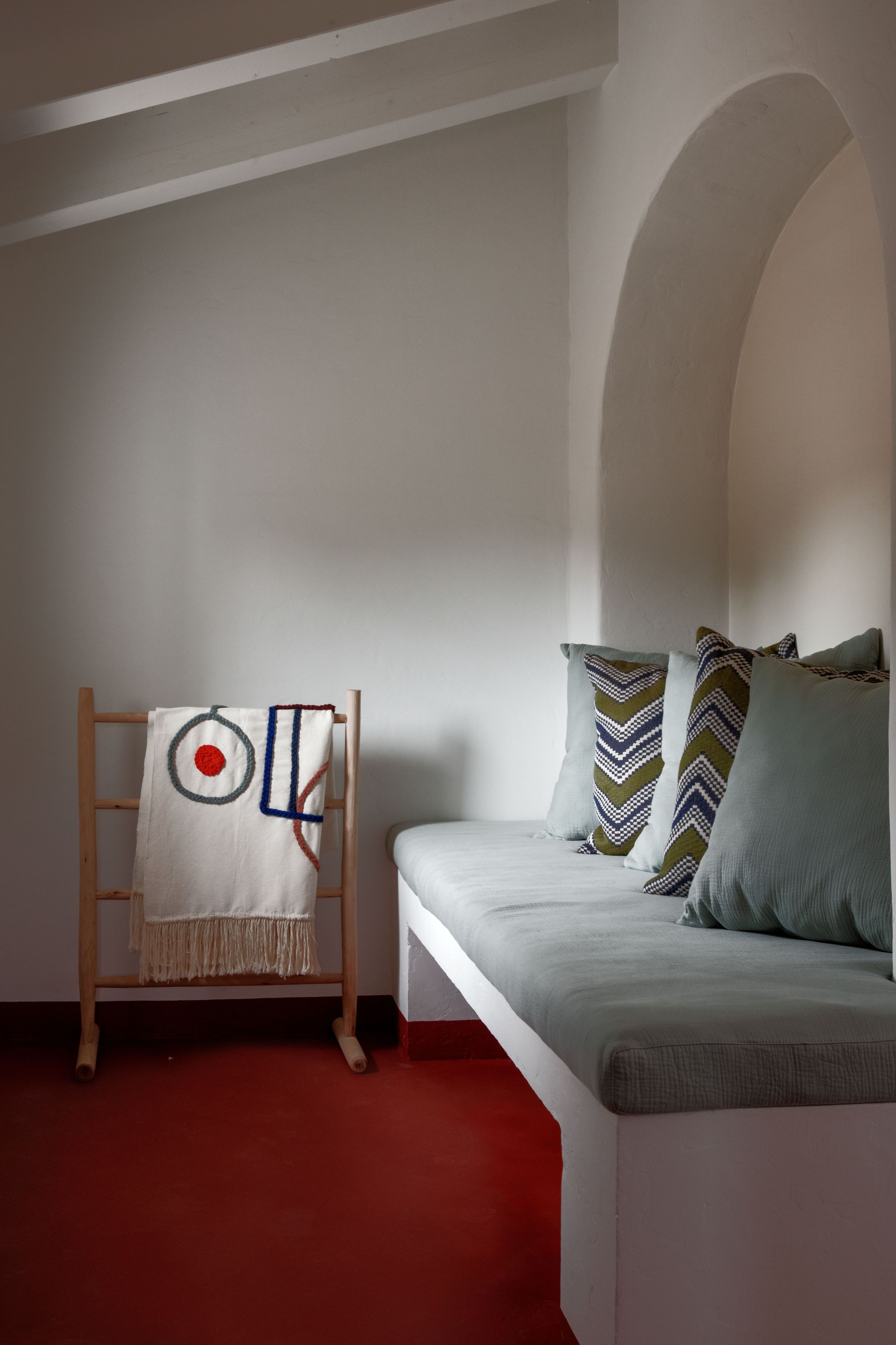 Una habitación con un sofá blanco, una escalera de madera y un plaid estampado.