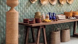 A wall with woven hats and a wicker vase.