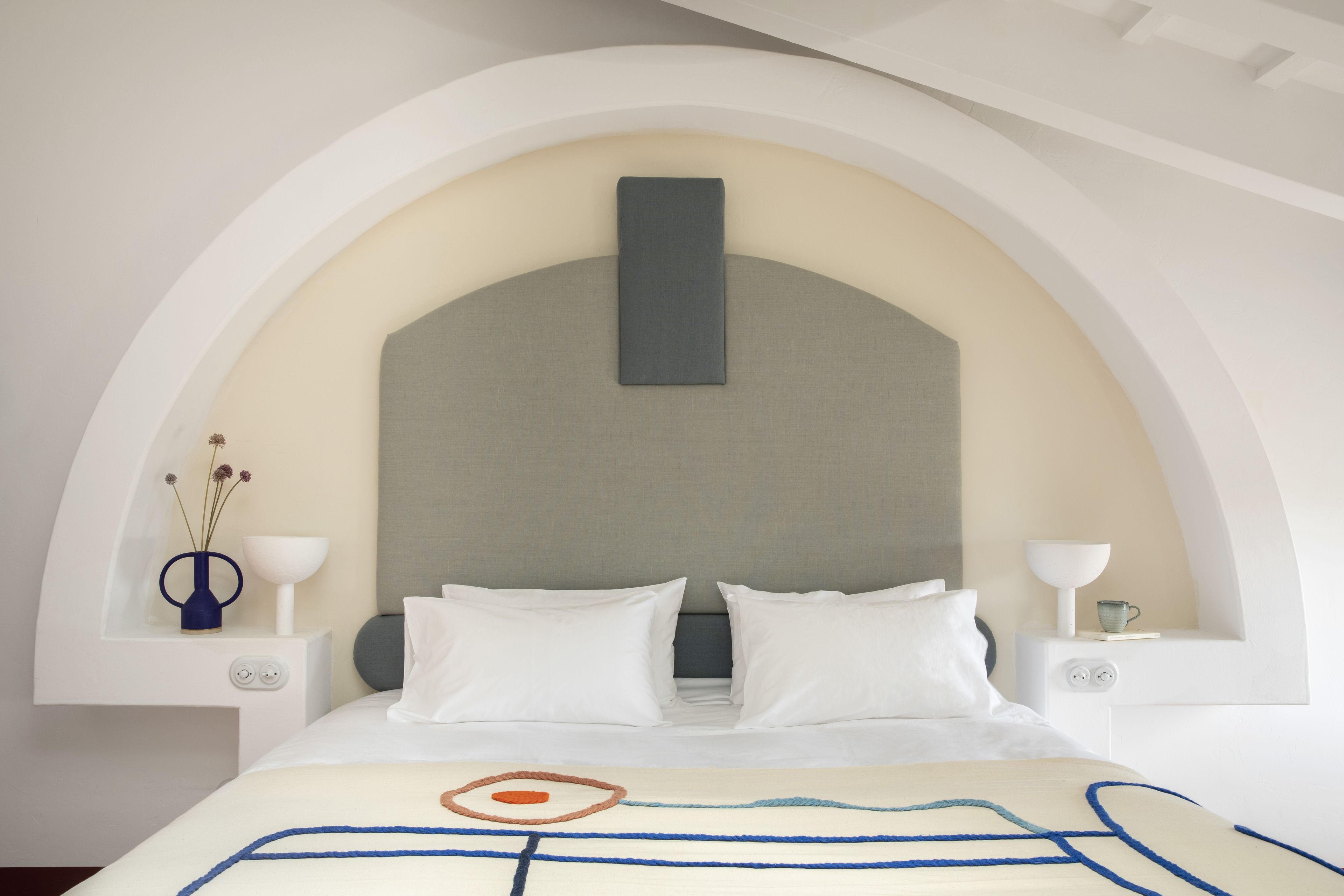 Una habitación de hotel moderna con una cama grande, ropa de cama blanca y un diseño minimalista.
