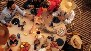 A round table with plates, glasses, and cutlery, surrounded by chairs.