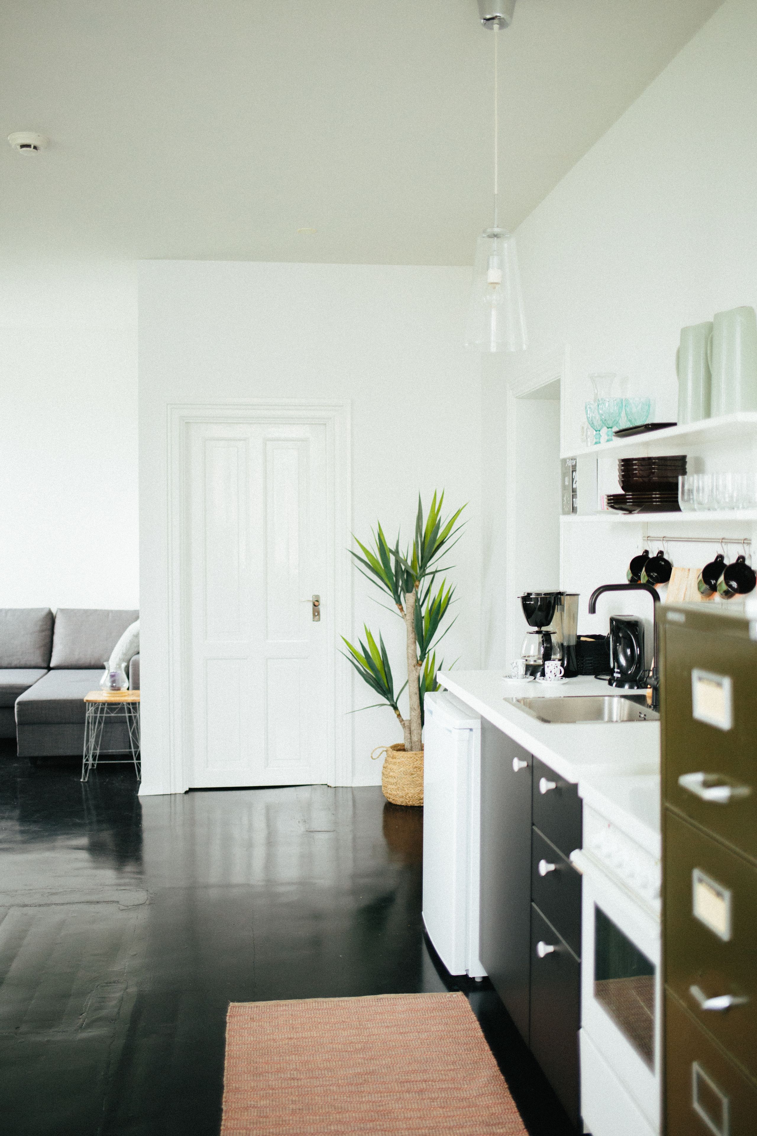 A modern kitchen with white cabinetry, a stainless steel sink, and a hanging light fixture.