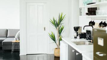 A modern kitchen with white cabinetry, a stainless steel sink, and a hanging light fixture.