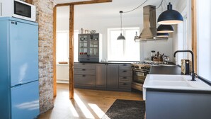 A modern kitchen with a blue refrigerator, grey cabinets, and a wooden ceiling. - Hoepfner  Historical House (Akureyri)