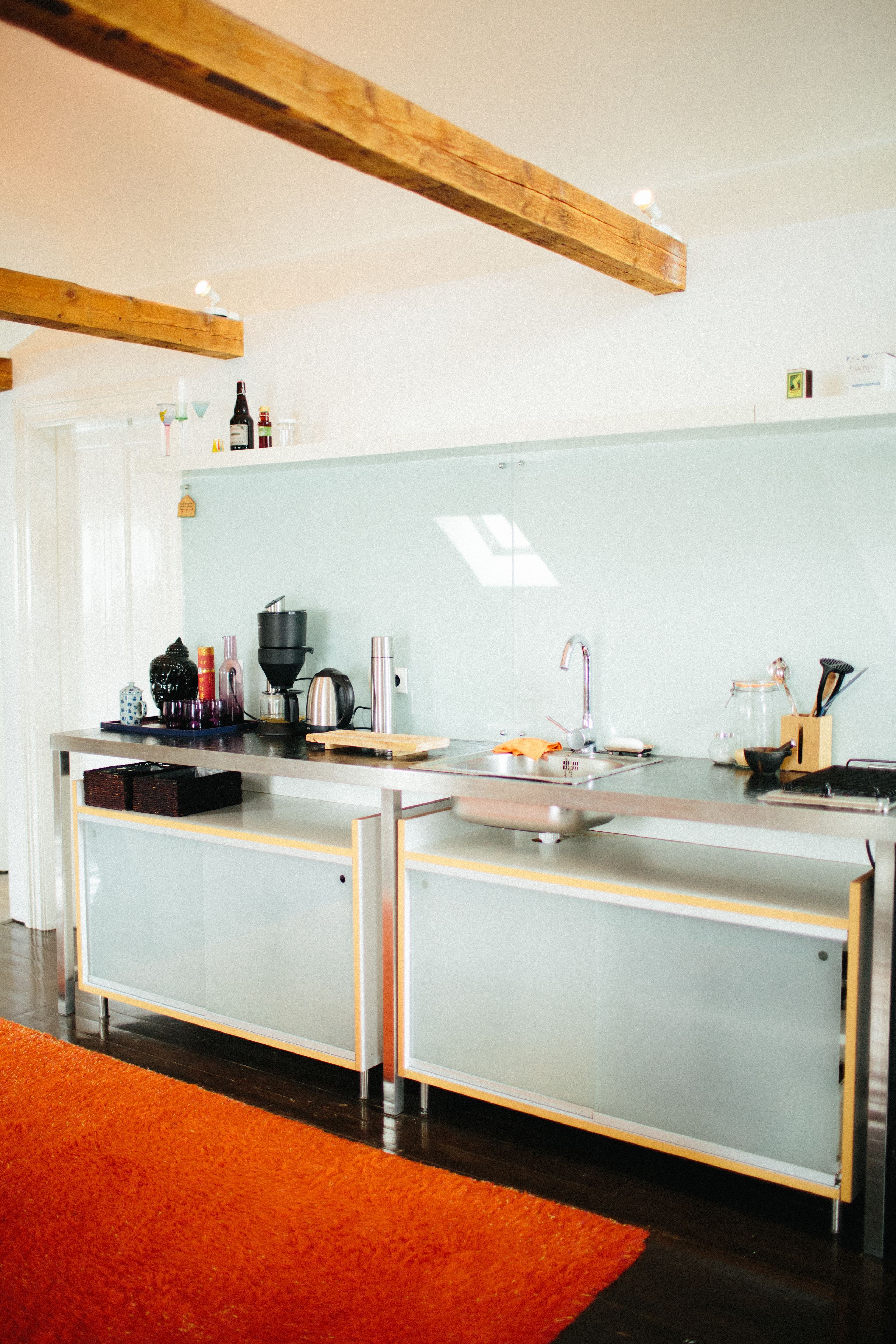 A modern kitchen with a stainless steel countertop, a coffee machine, and a sink.