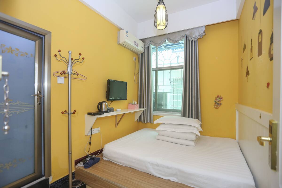 A bedroom with a bed, a TV, a heater, and a window with curtains.
