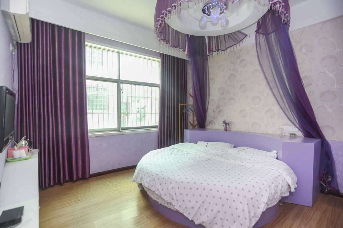 A bedroom with a bed, a vanity, and a window with curtains.