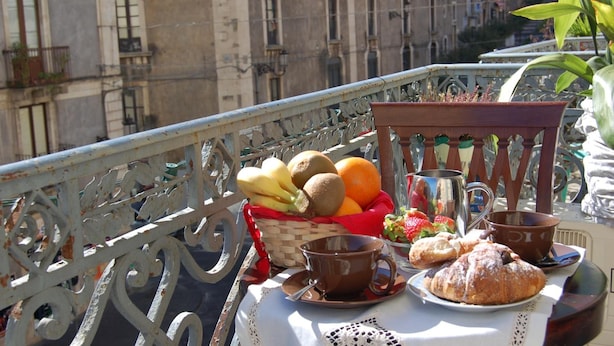 A balcony with a table set for breakfast, including fruits, pastries, and a coffee cup. - San Demetrio (Catania)
