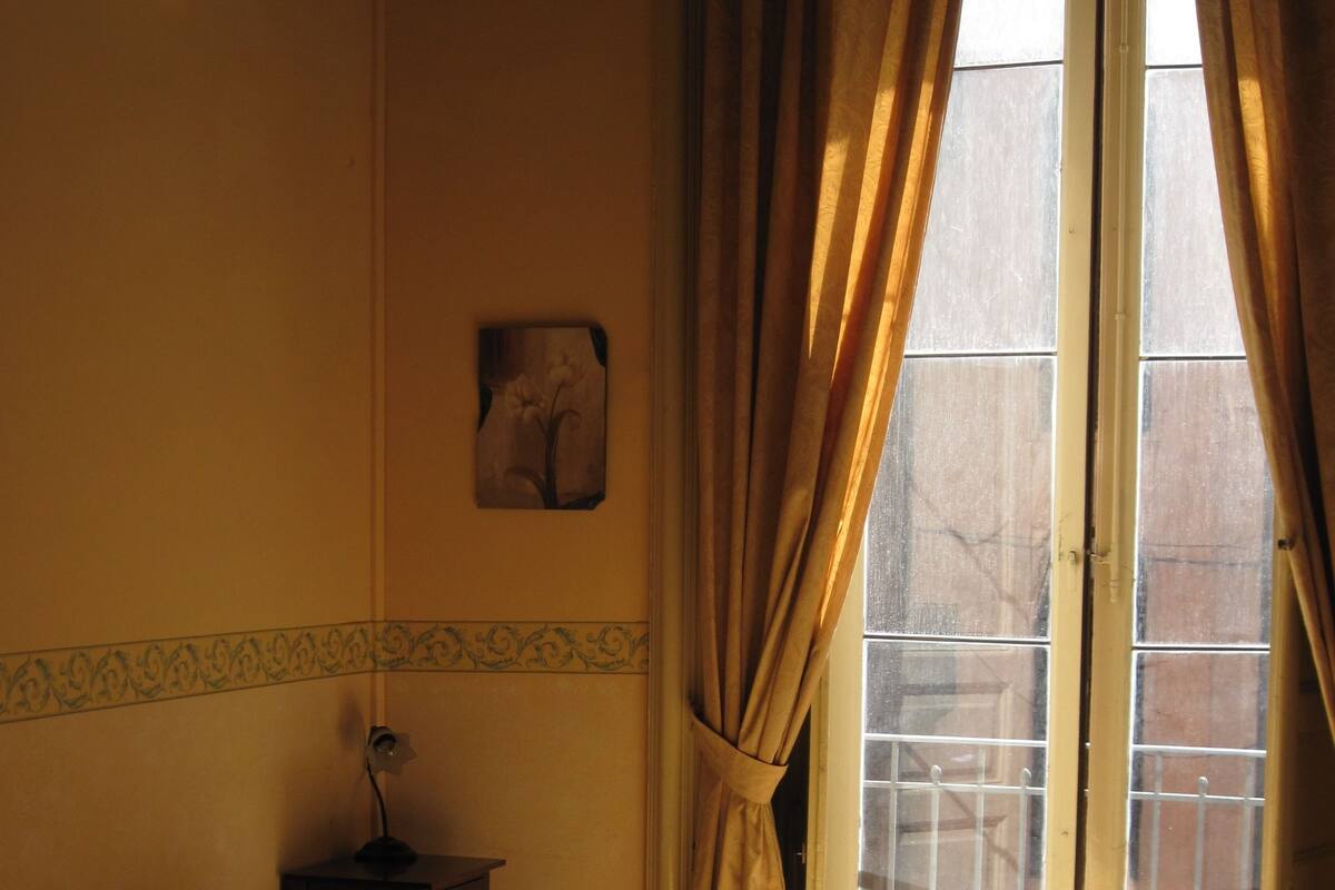 A room with a bed, a nightstand, and a window with curtains.