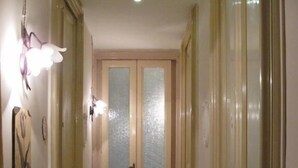 A narrow hallway with double doors, a light fixture, and a small table with items on it. - San Demetrio (Catania)
