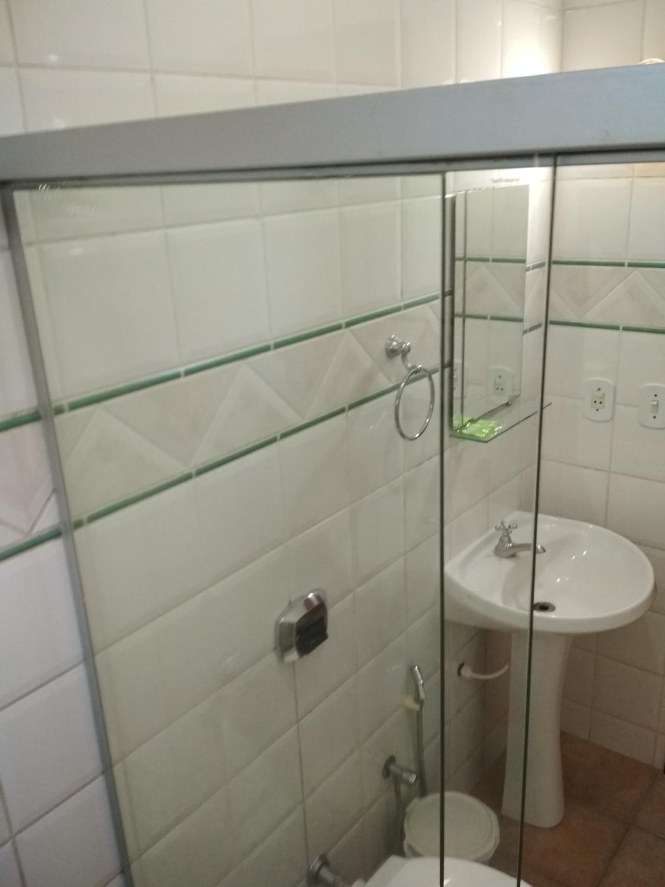 Bany amb dutxa tancada per vidre, un lavabo i un vàter.
