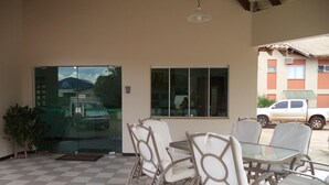 A covered patio with a checkered floor, a glass door entrance, and a table with chairs. - Villa Verde Hotel (Navirai)