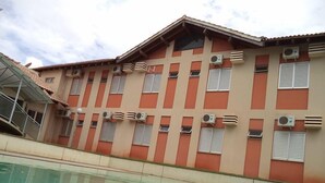 A building with multiple air conditioning units, a swimming pool, and a staircase leading to an upper level. - Villa Verde Hotel (Navirai)