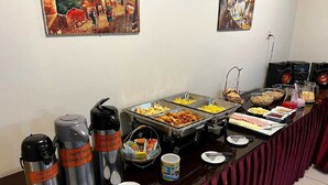 Una mesa de buffet con diversos alimentos, dispensadores de agua caliente y café, y un sistema de sonido.