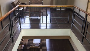 Un espacio interior de varios niveles con una zona central abierta, arreglos de asientos y una escalera.