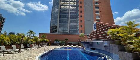 Alberca al aire libre, sombrillas en la alberca y camastros