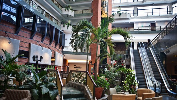 A spacious lobby with a central staircase, multiple levels, and a variety of seating areas.