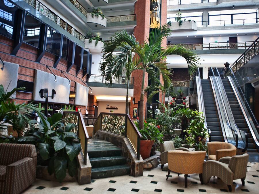 A spacious lobby with a central staircase, multiple levels, and a variety of seating areas.