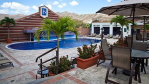A pool area with lounge chairs and a sign indicating a specific section.
