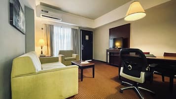 Une chambre d’hôtel équipée d’un canapé, d’un fauteuil, d’un bureau et d’une télévision.
