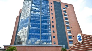A modern building with a glass facade and a brick base, featuring a prominent logo on the side.
