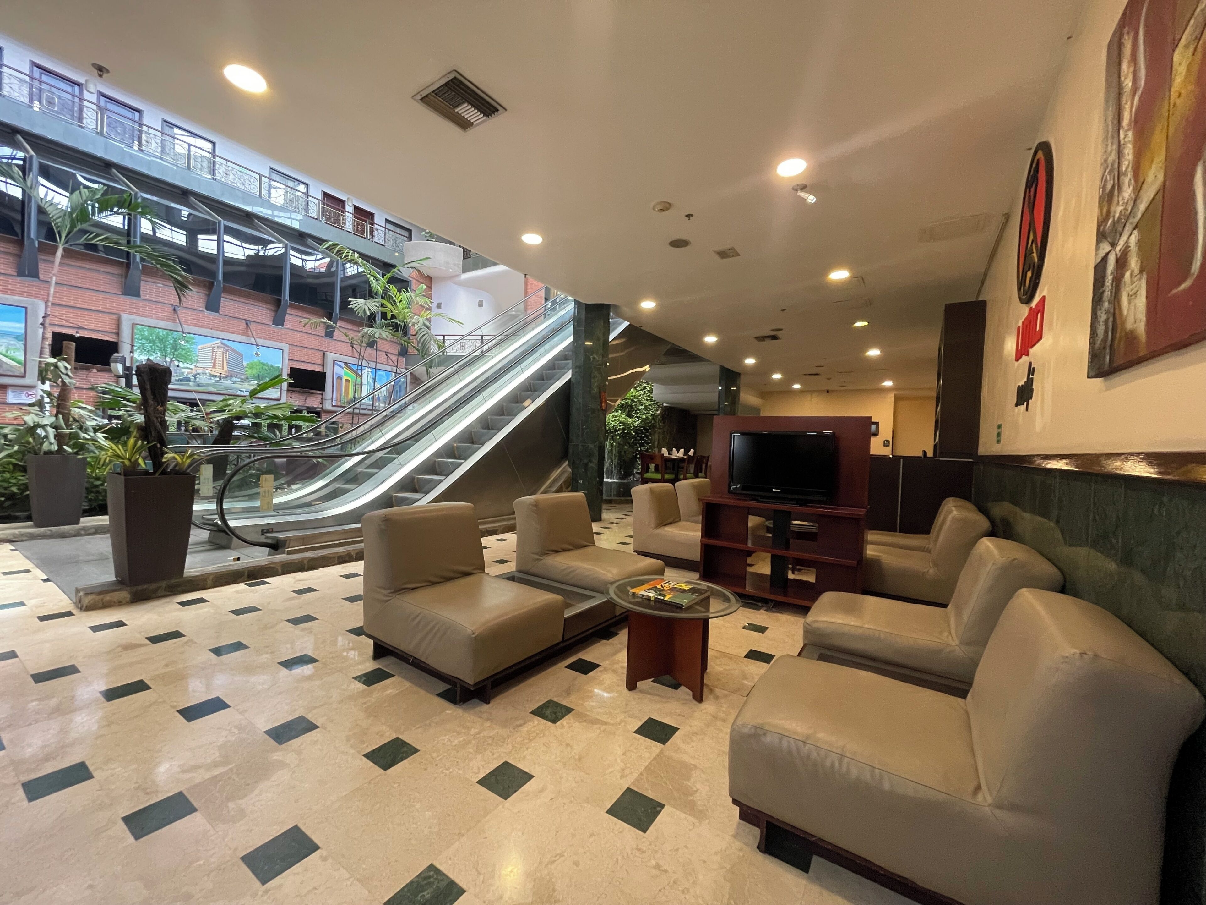 A lobby with a seating area, a TV, and an escalator.
