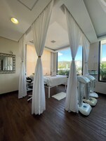 Una habitación con una cama, una camilla de masaje y un amplio ventanal con vistas.