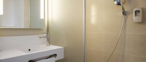 Baño con lavamanos blanco, espejo, ducha de mano y dispensador de jabón.