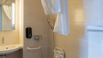 A bathroom with a sink, a hand dryer, a towel rack, and a shower curtain.
