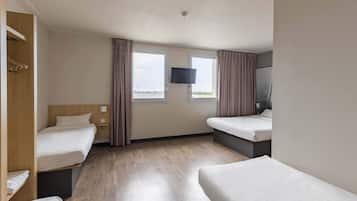 Een hotelkamer met twee bedden, een televisie en een raam met gordijnen.