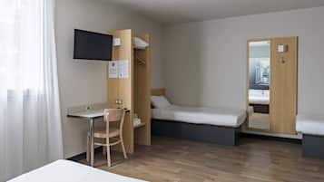 A hotel room with a bed, a desk, a chair, a TV, and a mirror.