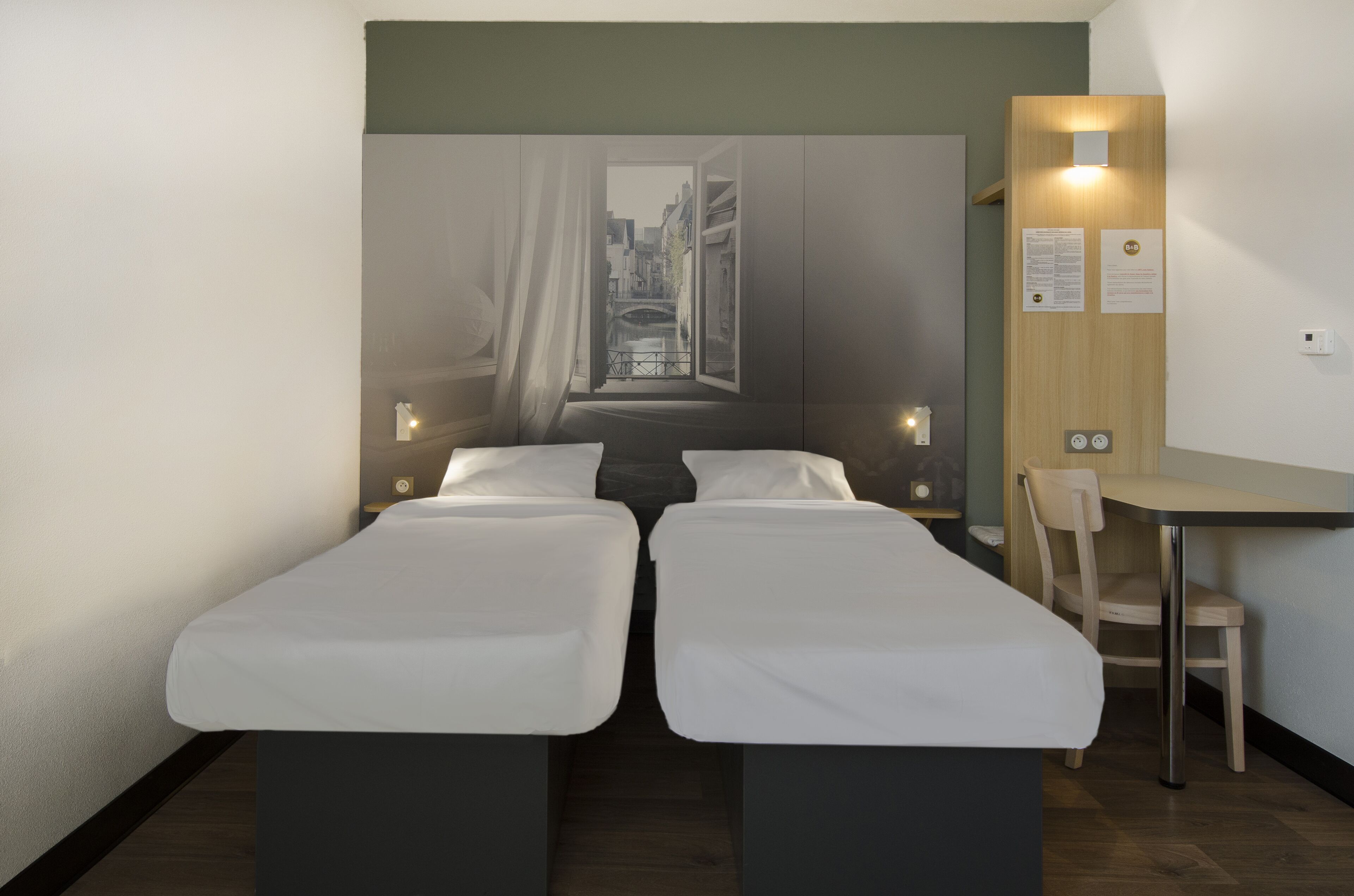 Una habitación de hotel con dos camas individuales, un escritorio y una silla.