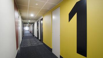 Ein Flur mit Teppichboden, Türen an beiden Seiten und der großen Zahl '1' an der rechten Wand.