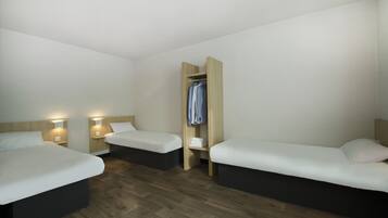 A hotel room with two beds, a wardrobe, and bedside lamps.