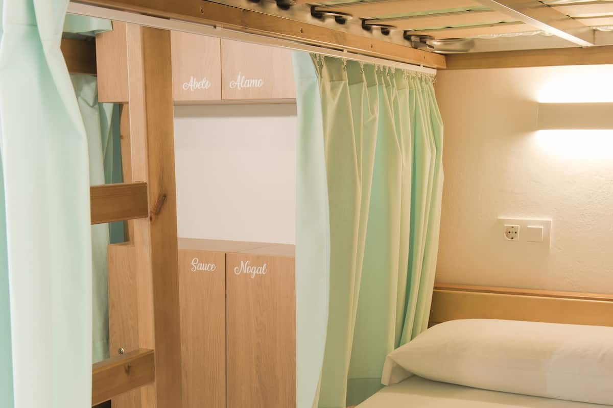 A bunk bed with a wooden headboard, a small desk, and a wardrobe with compartments labeled 'Abel' and 'Nega'.