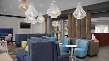 A hotel lobby with seating areas, a reception desk, and decorative lighting.