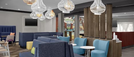 A hotel lobby with seating areas, a reception desk, and decorative lighting.
