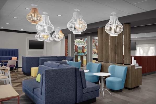 Un hall de hotel con zonas de estar, mostrador de recepción e iluminación decorativa.