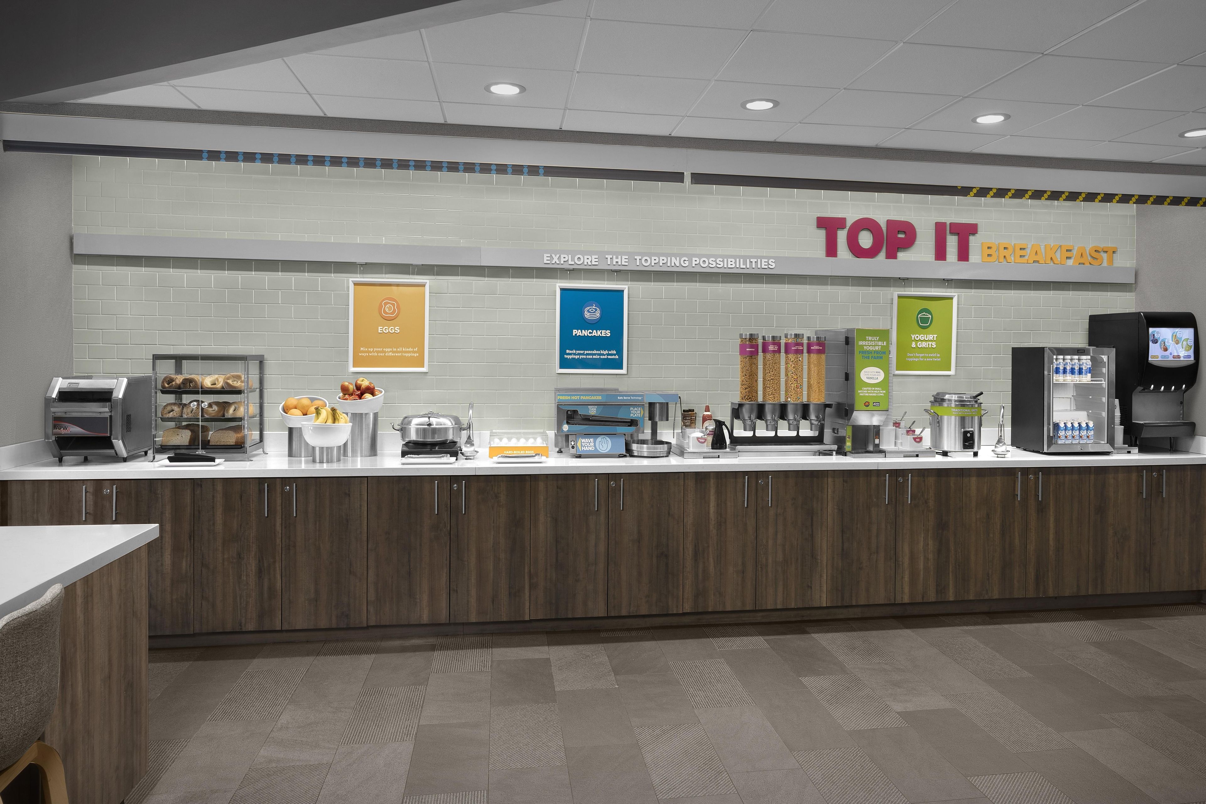 A breakfast counter with various food options and a sign that reads 'TOP IT BREAKFAST'.