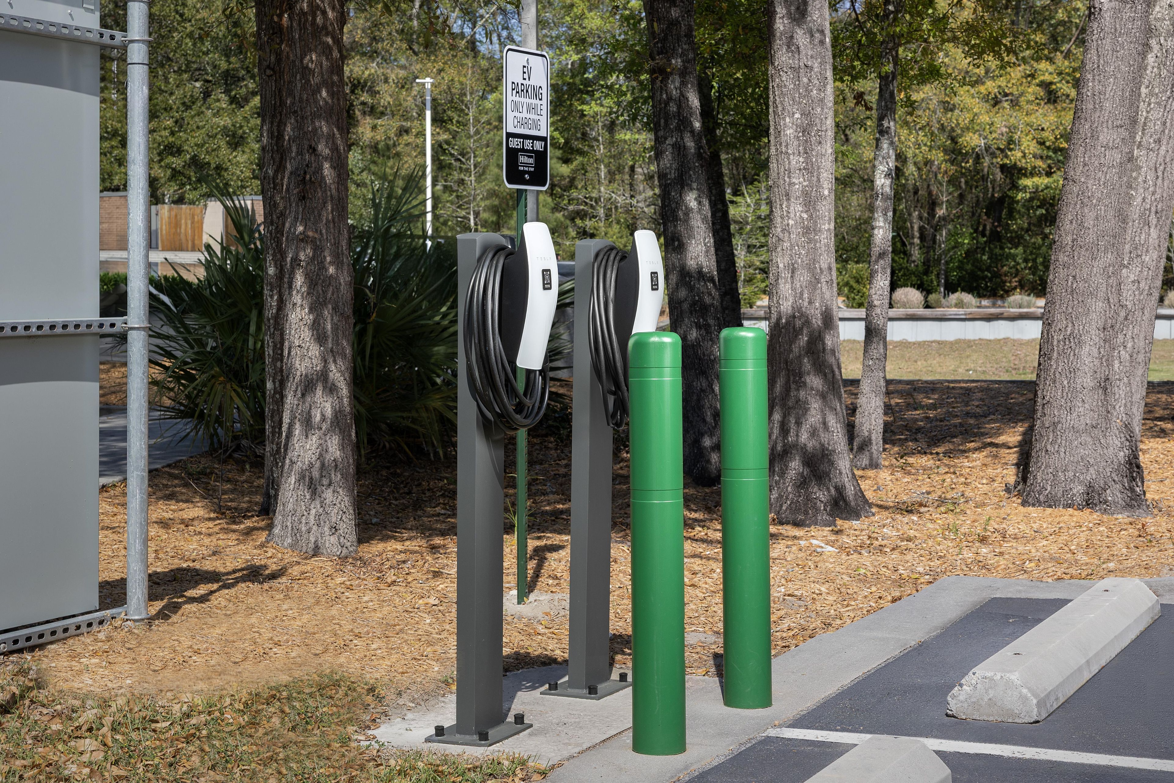 Una estación de carga para vehículos eléctricos con un letrero que indica uso exclusivo para huéspedes.